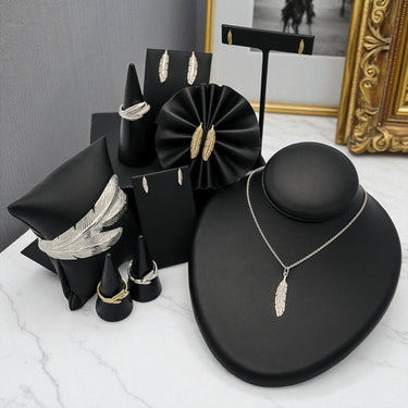 Sterling Silver and 14k Yellow Gold Jewelry in feather motif. Earrings, rings, cuff bracelet, pendant with chain are pictured. Several pieces have diamonds.